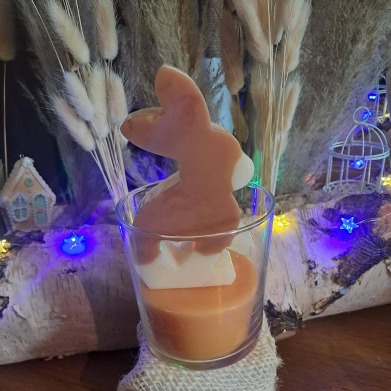 Bougie artisanale représentant un petit lapin bicolore avec un cœur sculpté, disponible en format pot de 265g ou palet de 80g, décoration de chambre et cadeau de naissance.