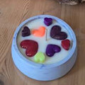 Bougie artisanale de 150g dans un pot effet marbre, décorée de multiples cœurs en cire de tailles et couleurs variées, design romantique et personnalisable.