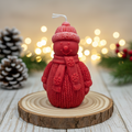 Bougie artisanale en forme de bonhomme de neige avec bonnet rouge, moulée à la main pour une décoration de Noël joyeuse et cocooning.