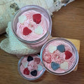 Bougie artisanale pochée à la main façon chantilly avec des petits cœurs en cire, présentée dans un verre recyclé, style gourmand et coloré.