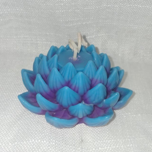 Bougie artisanale en forme de fleur de lotus avec un dégradé de couleurs allant du violet au bleu azur, posée dans une ambiance de décoration zen.