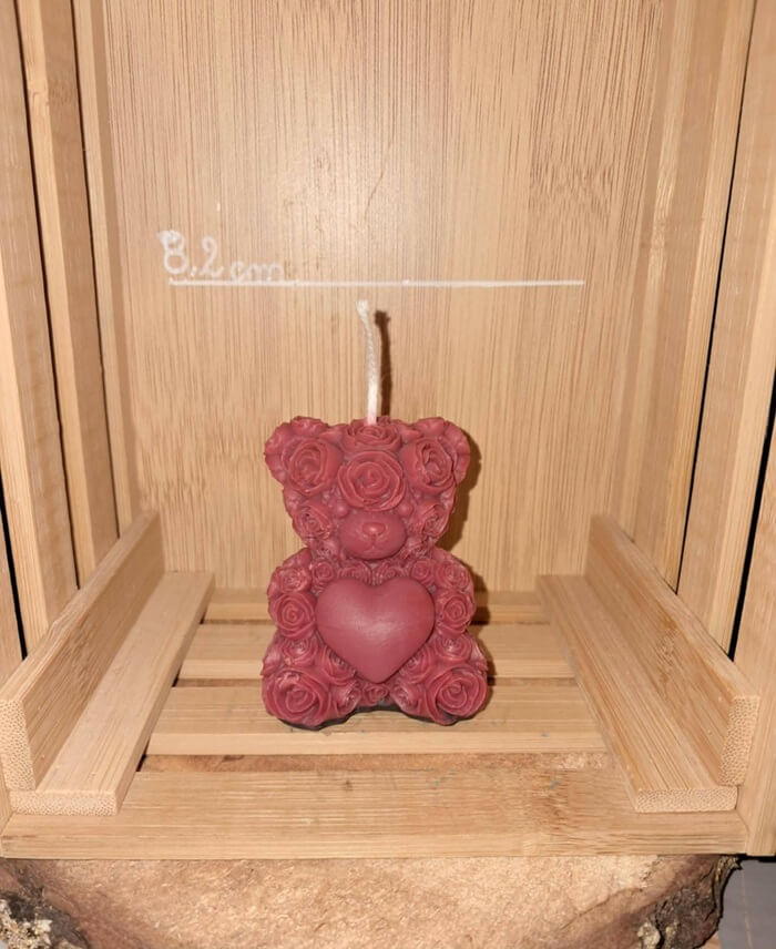 Bougie artisanale en forme d'ourson entièrement recouvert de roses sculptées et tenant un cœur entre ses pattes, cadeau romantique pour la Saint-Valentin.
