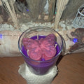 Bougie artisanale en verre avec un papillon rose sculpté sur le dessus, nommée L'Éveil d'Elya, symbole de renouveau et d'espoir.