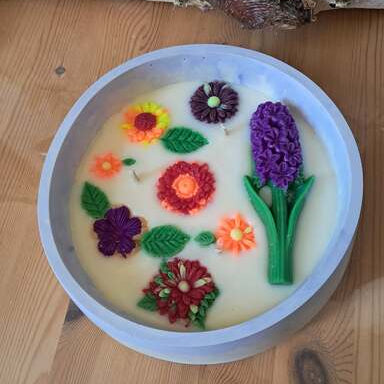 Grande bougie artisanale de 420g dans un pot effet marbre bleu, décorée d'un bouquet de fleurs sculptées en cire : jacinthe, marguerites et chrysanthèmes multicolores.