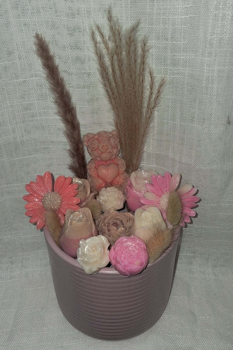 Prestigieux bouquet de fondants parfumés pesant plus d'un kilo, comprenant un ourson et des fleurs de cire dans un pot en bois naturel gravé réutilisable.