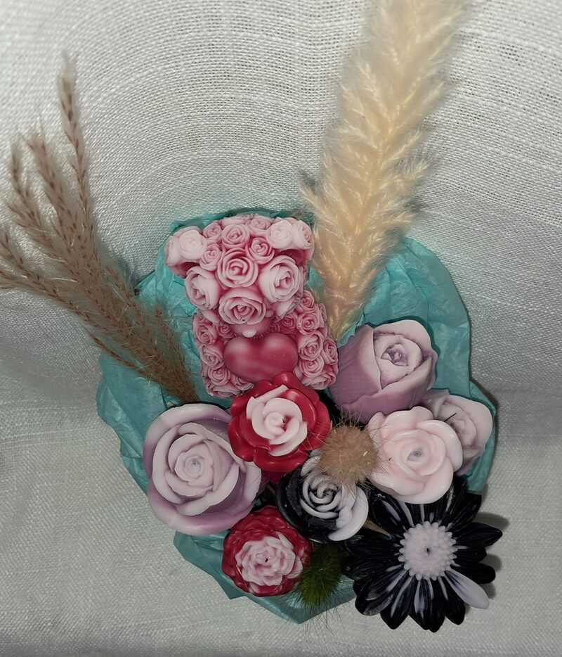 Composition florale artisanale de 410g composée d'un ourson de roses et de fleurs printanières, le tout contenu dans un pot entièrement sculpté en cire parfumée.