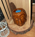 Brûle-parfum Bouddha en céramique marron avec fondant bleu dans un décor bois.