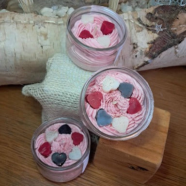 Bougie artisanale pochée à la main façon chantilly avec des petits cœurs en cire, présentée dans un verre recyclé, style gourmand et coloré.