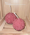 Duo de bougies artisanales en forme de sphères entièrement recouvertes de roses sculptées en relief, présentées ensemble comme objet de décoration romantique.