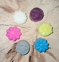 Assortiment de petits fondants parfumés artisanaux en forme de fleurs et de roses multicolores, fabriqués en cire végétale biodégradable.